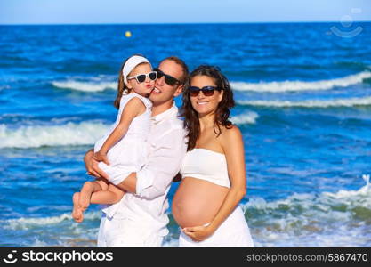 Happy family on the beach posing relaxed with pregnant mother woman