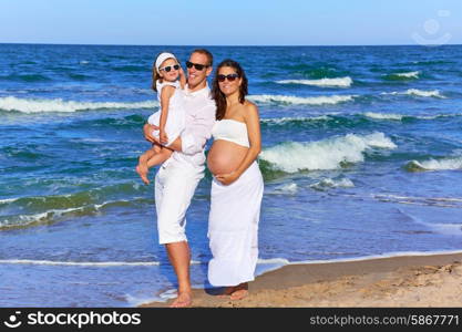 Happy family on the beach posing relaxed with pregnant mother woman