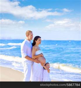 Happy family on the beach posing relaxed with pregnant mother woman