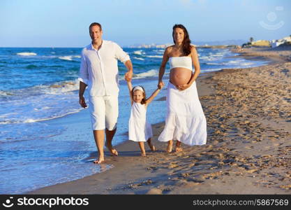 Happy family on the beach sand walking with pregnant mother woman