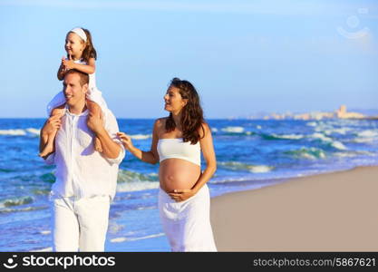 Happy family on the beach sand walking with pregnant mother woman