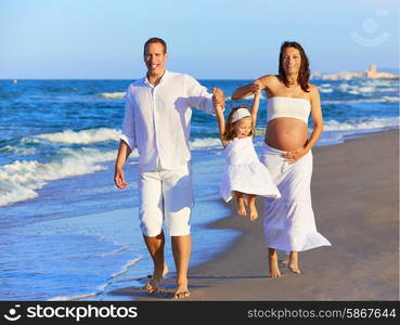 Happy family on the beach sand walking with pregnant mother woman