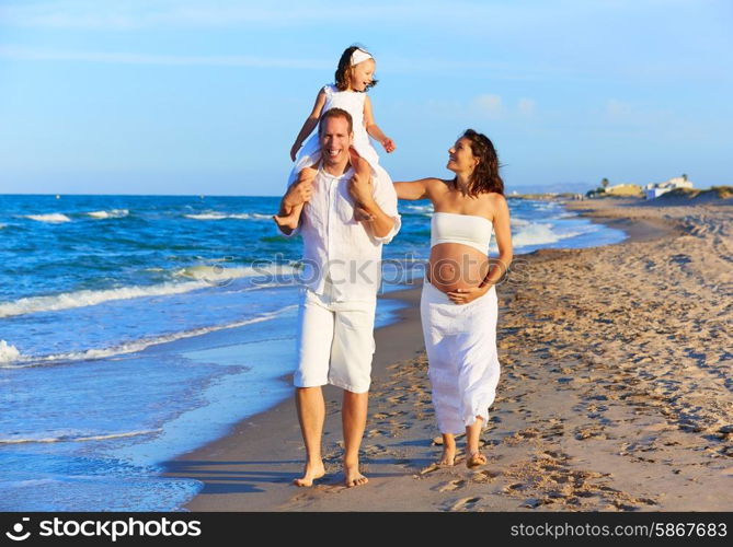 Happy family on the beach sand walking with pregnant mother woman