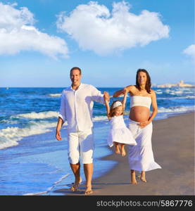 Happy family on the beach sand walking with pregnant mother woman