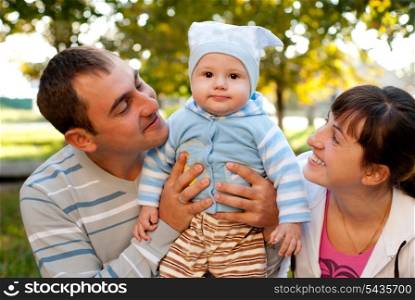 Happy family outdoor - mother, father and son are smiling