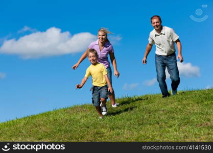 Happy family outdoors is running on a dirt path on a beautiful summer day - they try to catch each other