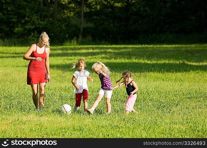 Happy family playing football (well, soccer for North America) on a green, sunlit meadow