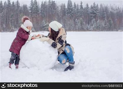 Happy family playing snowballs in the winter snowy day. Happy family of mom and kid enjoy winter snowy day