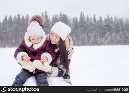 Happy family playing snowballs in the winter snowy day. Happy family of mom and kid enjoy winter snowy day