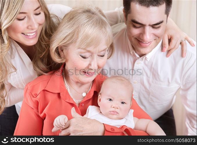 Happy family portrait, cheerful mother and father standing near granny holding newborn baby on hands, love and togetherness concept