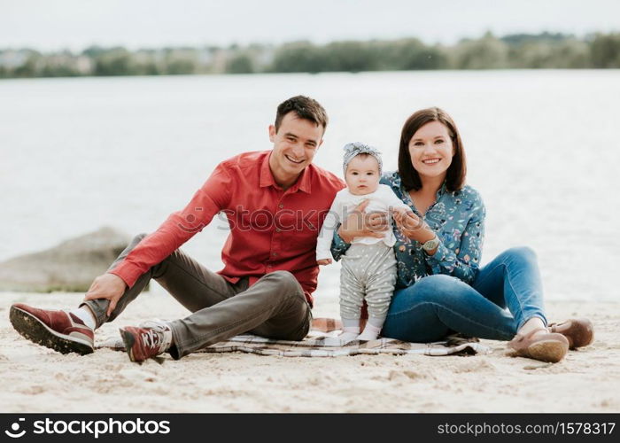 happy family resting by the lake. family with a small child.. happy family resting by the lake. family with a small child