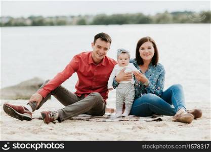 happy family resting by the lake. family with a small child.. happy family resting by the lake. family with a small child