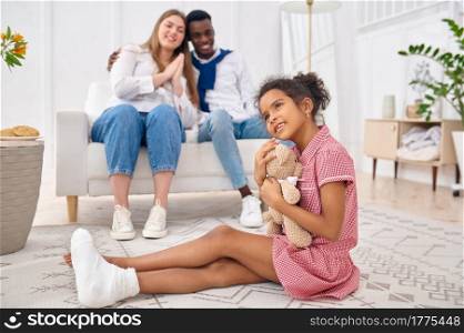 Happy family resting in living room. Mother, father and their daughter poses at home together, good relationship. Mom, dad and female child. Happy family resting in living room