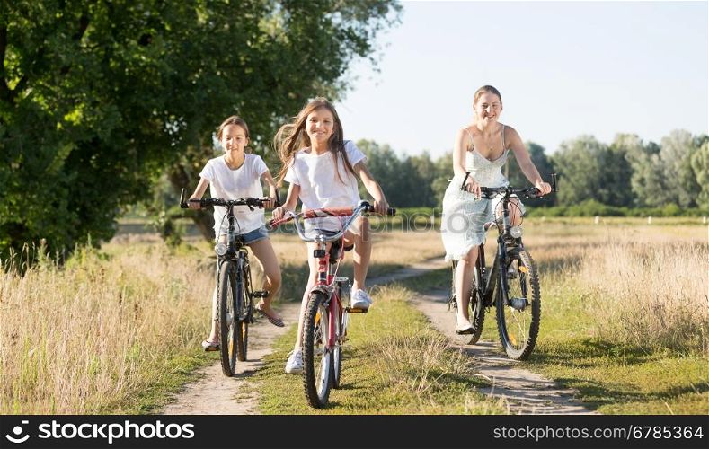 Happy family riding on bicycles in meadow at sunny day