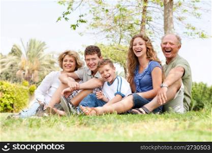 Happy family siiting in the park and smiling at camera