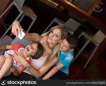 Happy family siting on sofa and using cell phone for video call at home