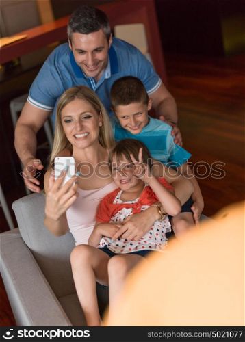 Happy family siting on sofa and using cell phone for video call at home
