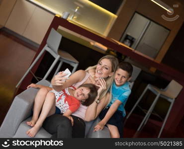 Happy family siting on sofa and using cell phone for video call at home