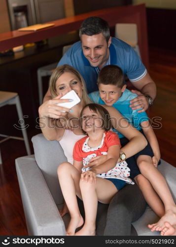 Happy family siting on sofa and using cell phone for video call at home