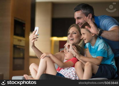 Happy family siting on sofa and using cell phone for video call at home