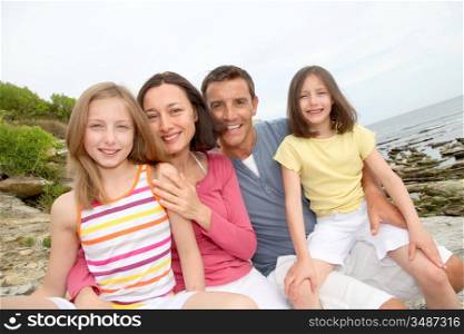 Happy family sitting by beach at low tide