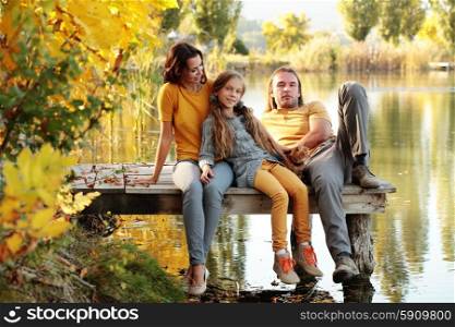 Happy family sitting by the lake