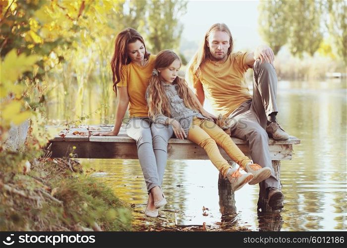 Happy family sitting by the lake