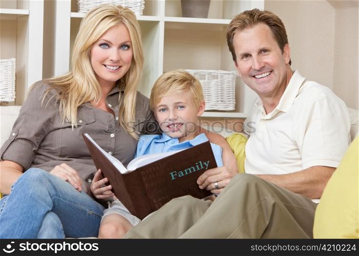 Happy Family Sitting on Sofa Looking at Photo Album