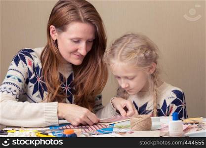 happy family - smiling Mom and daughter make a New Year's card, scrapbook