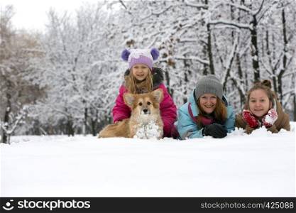 happy family - smiling mother and daughters with little cute corgi fluffy puppy at the winter day