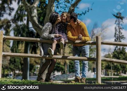 Happy family standing in park while little girl looking at camera