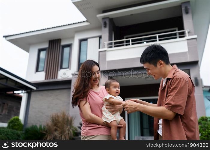 happy family standing outside their house, husband and wife and baby