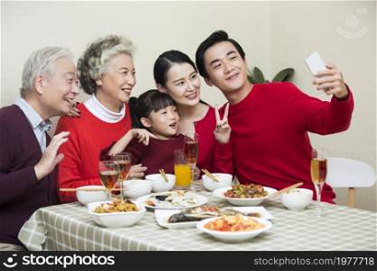 Happy family taking photos together over the New Year's reunion dinner