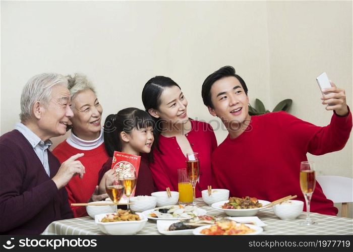 Happy family taking photos together over the New Year's reunion dinner