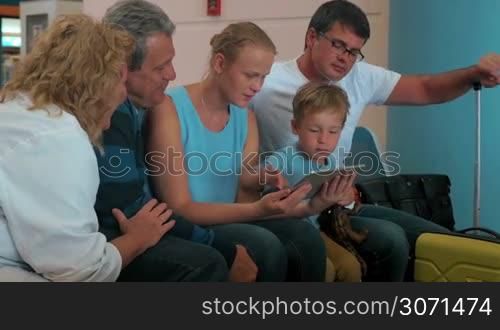 Happy family talking in the airport while using tablet pc computer for entertainment