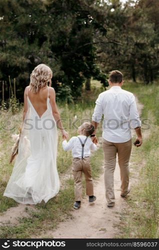 happy family three dad mom and son on a walk in the woods