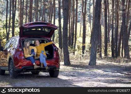 happy family travel by car. mother and daughter sitting in the trunk of a car 