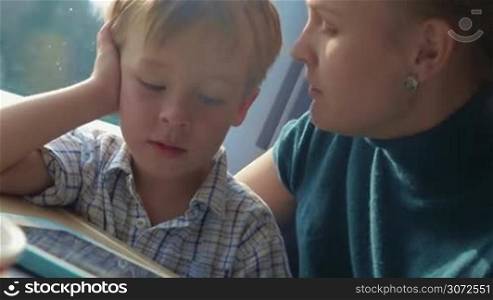 Happy family travel by train. Mother talking to the little son who playing on digital tablet and they kissing each other
