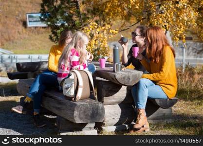 happy family trip. girls have a rest and drink tea while traveling in the mountains