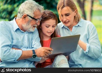 Happy family using laptop computer together in the garden park in summer. Kid education and family activities concept.