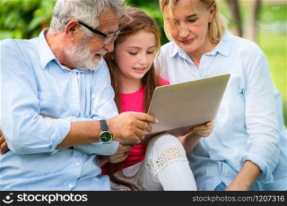 Happy family using laptop computer together in the garden park in summer. Kid education and family activities concept.. Happy family using laptop computer in public park.