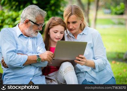 Happy family using laptop computer together in the garden park in summer. Kid education and family activities concept.