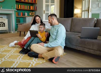Happy family using mobile tablet at home together. Father and mother with son watching joyful video on digital device spending time on weekend. Happy family using mobile tablet at home together