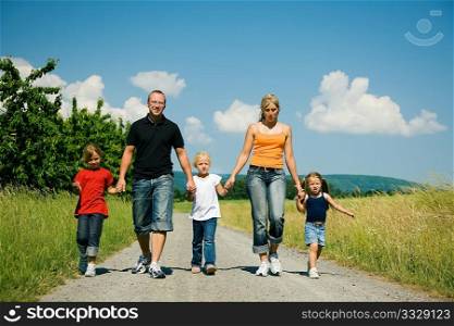 Happy family walking down a path on a bright summer day