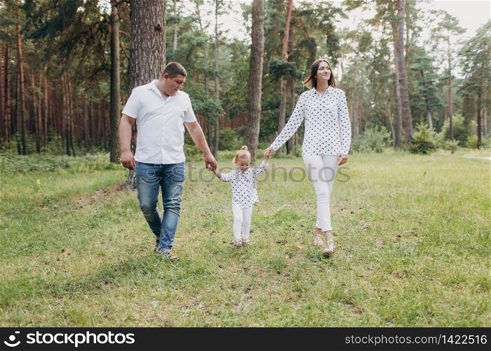 happy Family walking in the park holding hands and smiling. mom, dad and daughter spending time together outdoor on a summer day. selective focus.. happy Family walking in the park holding hands and smiling. mom, dad and daughter spending time together outdoor on a summer day. selective focus
