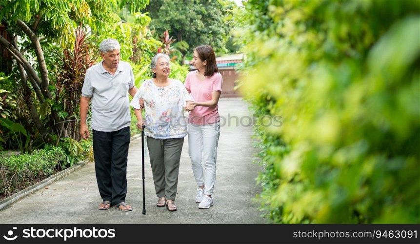 Happy family walking together in the garden. Old elderly using a walking stick to help walk balance. Concept of  Love and care of the family And health insurance for family
