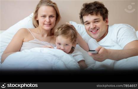 Happy family watching television in the bedroom
