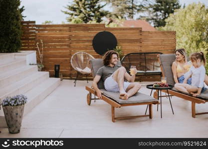 Happy family with a mother, father and daughter sitting on the deck chairs by the swimming pool