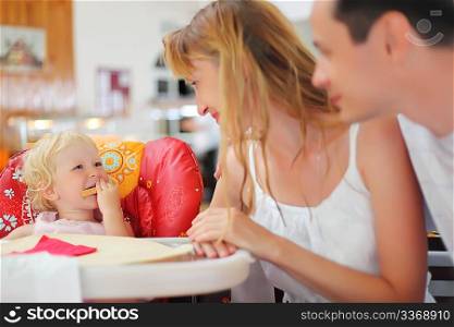 Happy family with blond little girl eating bread