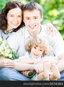 Happy family with bouquet of spring flowers against blurred green background